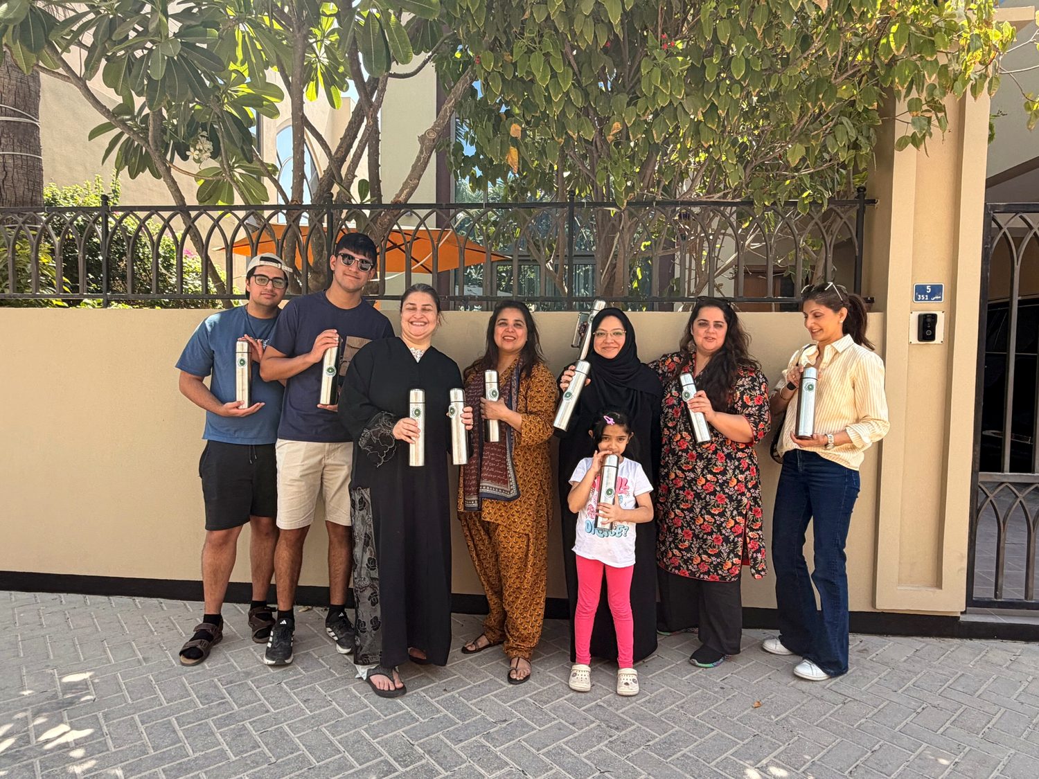 Volunteers holding water bottles outside a house