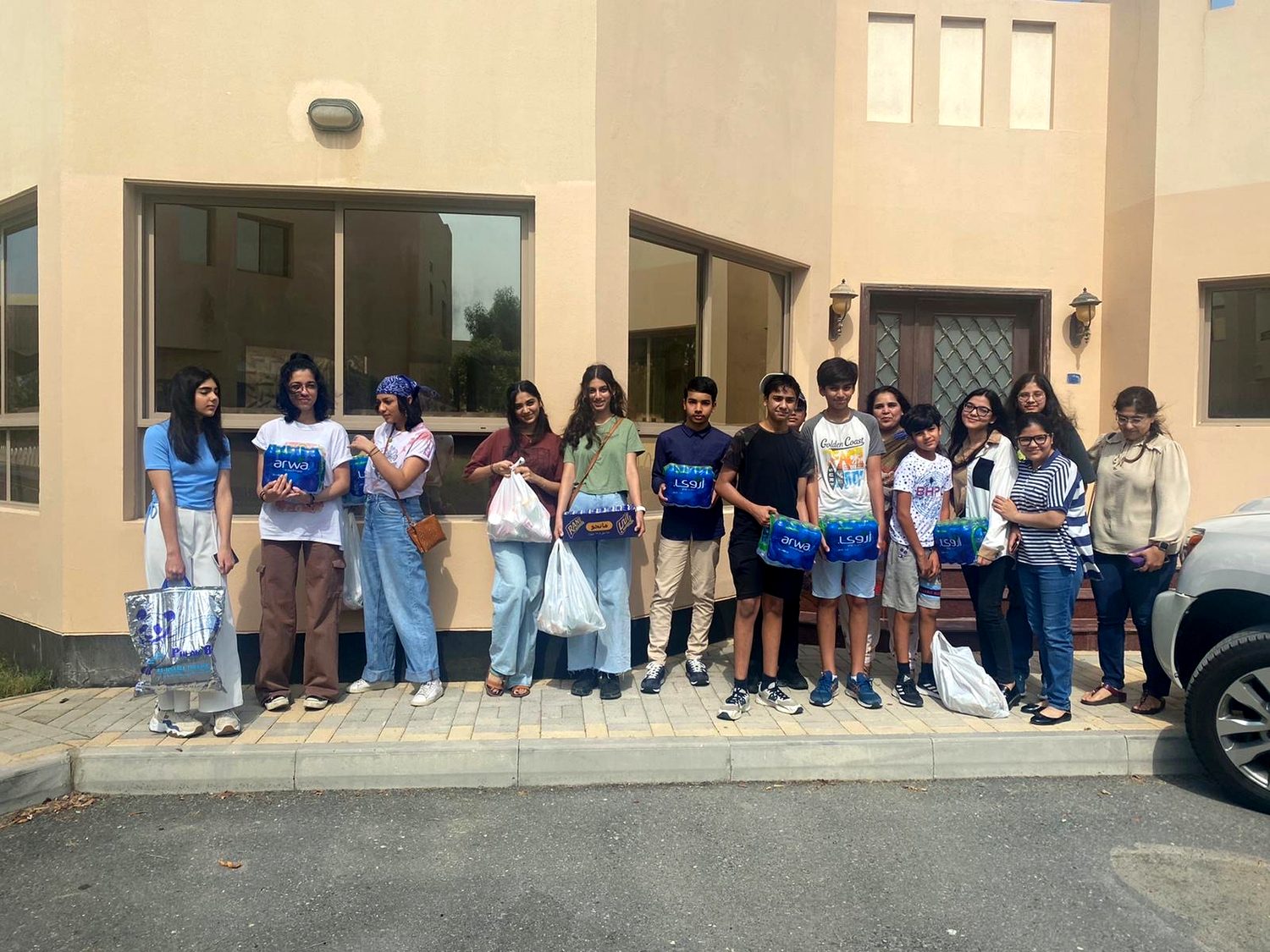 A line of young volunteers holding donation bags outside a building